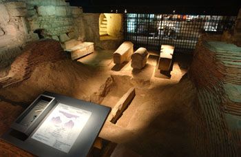 Vue de la crypte archologique. Cette premire section, jusqu'aux grilles, correspond  la zone de fouilles de Viollet-le-Duc. On peut distinguer, sur le mur gauche, au fond, les blocs de remploi antique, plus prs la fosse de Denis et diffrents sarcophages de pierre de l'Antiquit Tardive. P.Cadet  CMN 